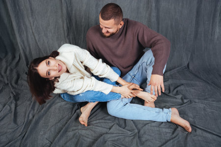 Portrait of a smiling pretty girl and her beautiful boyfriend. The couple sit cross-legged and hug....