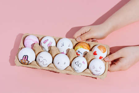 Childrens hands hold painted Easter eggs on a pink background. Minimal concept. Top view. Copy space.の写真素材