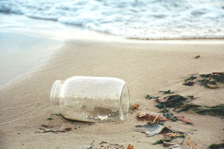 Garbage, waste on the seafront. glass jar. The concept of cleaning the coastal zone and protecting the environment.の写真素材