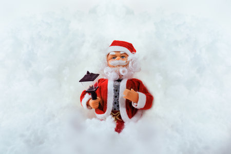 Toy doll Santa Claus on a white snowy background with space for text or image.の写真素材