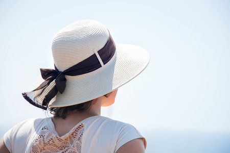 Back view soft focus on a young girl standing in a hat on her head from the sun with a ribbon with a...