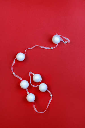 White garland ornaments Christmas decoration on a red background. Round balls shining toys with ribbon. Flat lay. Soft selective focus. Copy Space for text.の写真素材