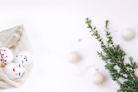Concept of combination of spring and winter holidays. Christmas garland on tree branch and Easter...
