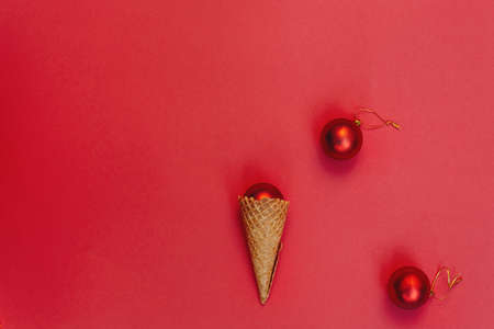 Christmas decoration in a waffle cone on a red background. Round toys with gold thread. Alternative Concept of celebrating winter holidays, top view festive composition. Flat layの写真素材