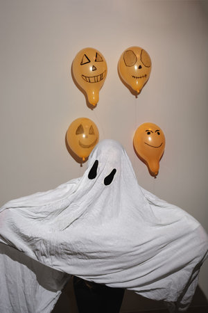 Happy Halloween. Child is dressed in white sheet and looks like ghost. Suit is made by hand. Painted...