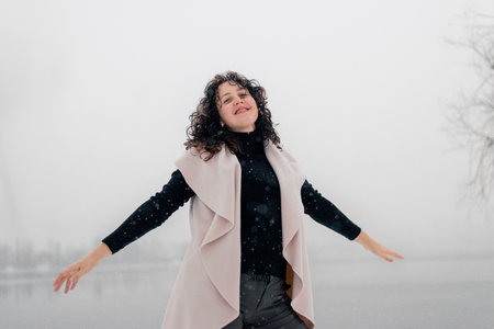 Soft Selective focus Beautiful girl with long curly hair is circling under snow and snowflakes and enjoying outdoor life. Merry Christmasの写真素材