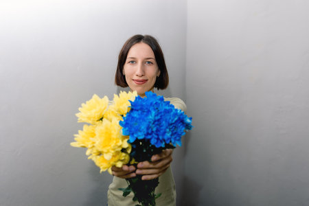 Defocused focus on flowers in the foreground. The girl is holding blue and yellow flowers as the national flag of Ukraine. Copy space for text.の写真素材