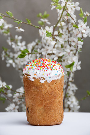 Traditional Easter cake with white meringue decorated with sugar or sweet bread, blooming white cherry branches, Front view. Free copy space.の写真素材