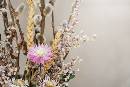 dried flowers. Composition for Easter - willow twigs, yellow wheat spike, small white and pink flowers on gray background. Bright sun rays. happy holidays. Card with Copy Space for textの写真素材