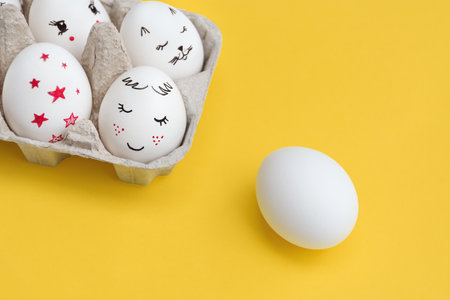Easter card. White Eggs painted with smiles and one left blank for writing. yellow background. Top view with Copy Space. happy holidays.の写真素材