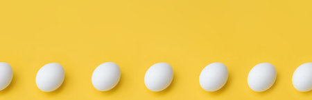 Banner made from White chicken eggs in row on yellow background, top view. copy space