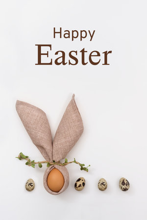 Happy Easter lettering. Bunny with funny ears made of napkin and Easter egg on white background. Quail eggs. Postcard template in a minimalist style. Copy space, flat layの写真素材