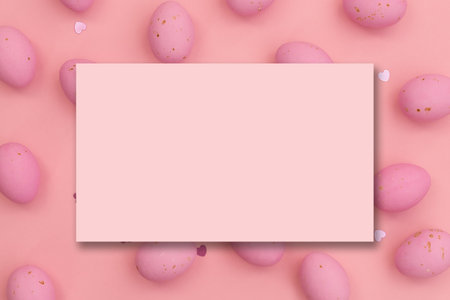 Easter postcard. Invitation mockup or blank pink card on pink chocolate easter eggs. Shimmering glowing hearts. happy holidays. copy spaceの写真素材
