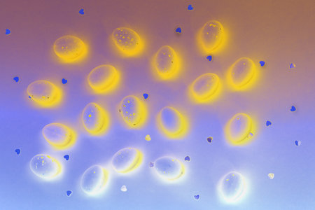 Easter abstract card. Brightly illuminated eggs yellow color on blue background. Shimmering glowing hearts. Ideal for Easter and spring themes, use in marketing materials, packaging. happy holidaysの写真素材