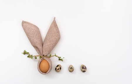 happy easter card. Bunny with funny ears made of napkin and Easter egg on white background. Quail eggs. Postcard template in a minimalist style. Copy space, flat layの写真素材