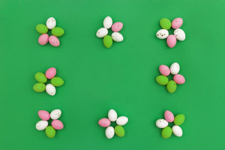 Happy Easter concept. Colorful chocolate eggs arranged in shape of flowers, which form frame on green background. Use for Easter or spring advertising as decorative image for blog. Top view.Copy Spaceの写真素材