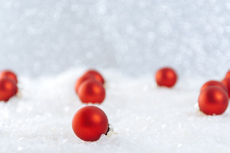 greeting winter card. Red balls, Christmas toys among snow on bright bokeh background. Copy space for your designs. merry christmasの写真素材