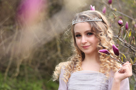 young beautiful girl in a light lilac dress in the garden where magnolias bloomの写真素材