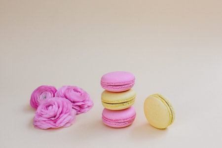 Macaroons and ranunculus on a yellow background.