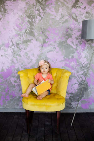 Little girl is sitting in a chair.の写真素材
