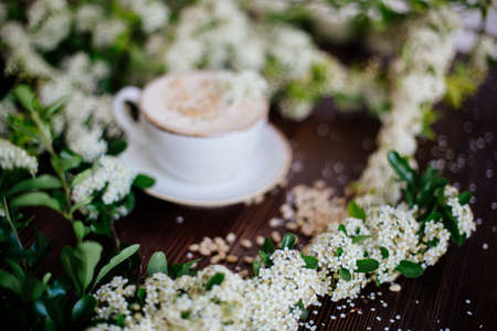 Coffee in hand and white flowers.の写真素材