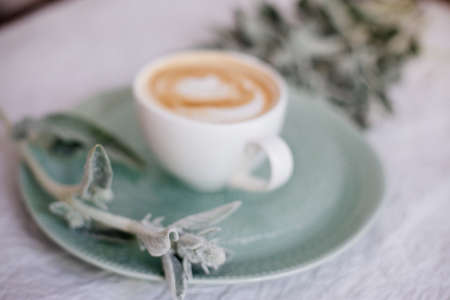 A cup of cappuccino and flowers on a wooden table.の写真素材