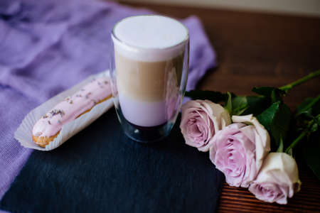 A cup of violet latte on a table with eclair and roses.の写真素材