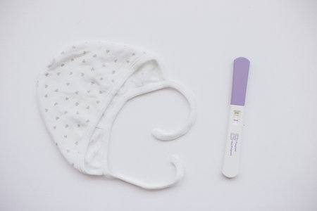 A positive pregnancy test with a photograph of ultrasound and a baby cap.の写真素材