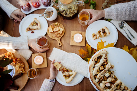 Overview of picnic food served on tablecloth and several humans taking snack.の写真素材