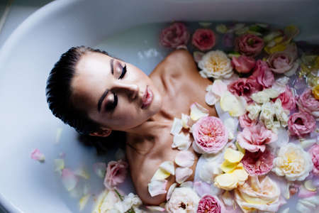 Beautiful girl in the bathroom with many flowers.の写真素材