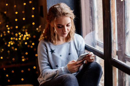 Woman with a phone by the window.
