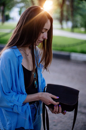 Girl is holding a clutch bag.