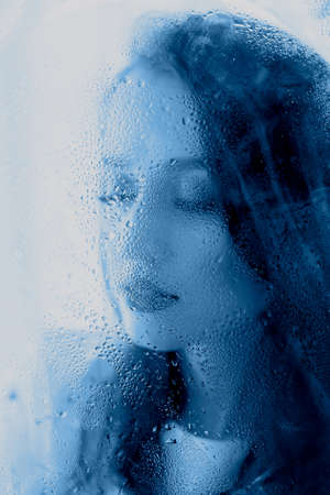 Beautiful woman on blue color by the window.の写真素材