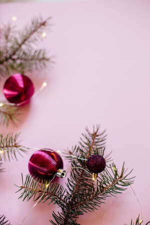 Christmas border with fir branches, christmas balls and ornaments on pastel pink background.の写真素材