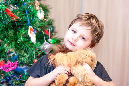 A boy with toys in his hands under a Christmas treeの写真素材