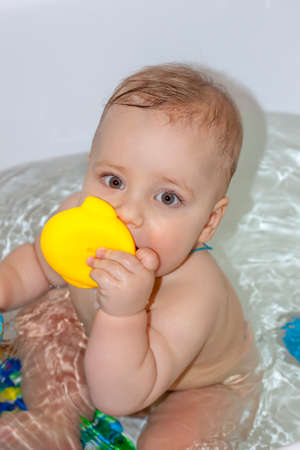 The child is bathing in the bath. Games in the water. Bathing a child. Toys in the bathroom. Portrait of a baby.の写真素材