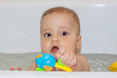 The child is bathing in the bath. Games in the water. Bathing a child. Toys in the bath.
