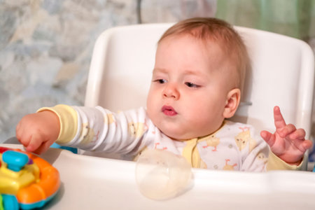 A child in a child seat. The baby is playing with toys sitting in a chair. The emotions of a child.の写真素材