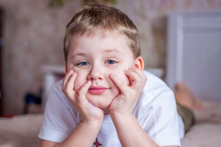 The boy lies on the bed and dreams. The emotions of a child. Portrait.の写真素材