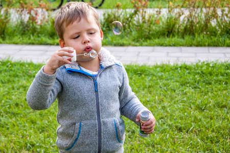 A boy on the street blows soap bubbles.の写真素材