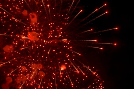 Salute. Bright, red splashes of fireworks in the dark sky. Night fireworks.