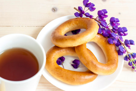 Tea with bagels. Butter the bagels. Fragrant tea. Light composition with bright and purple flowers....