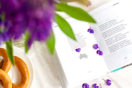 Sweet bagels and tender lupine flowers. Light composition with bright and purple flowers. A gentle and romantic morning with tea and a book. A book of poems for Breakfast.の写真素材