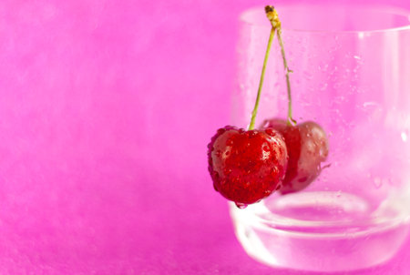 Sweet cherries. Red cherries hang on a transparent glass. Ripe berry. Bright summer background for presentations and graphic works.の写真素材