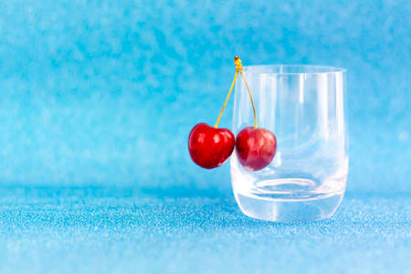 Sweet cherries. Red cherries hang on a transparent glass. Ripe berry. Bright summer background for presentations and graphic works.の写真素材