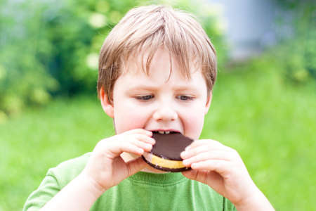 The boy bites down on the ice cream. Delicious ice cream in the hands of a child.の写真素材