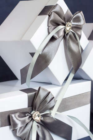 The gift box is white with a beautiful gray bow. Gift on a dark background. Holidays and surprises. Satin bows with rhinestones.の写真素材