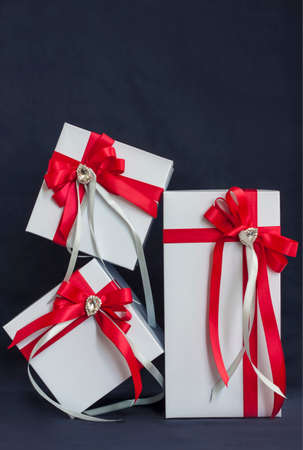 The gift box is white with a beautiful red bow. Gift on a dark background. Holidays and surprises. Satin bows with rhinestones.の写真素材