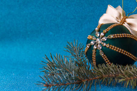 Christmas ball for Christmas tree decoration on blue background. Spruce branch and Christmas ball in rhinestones.の写真素材