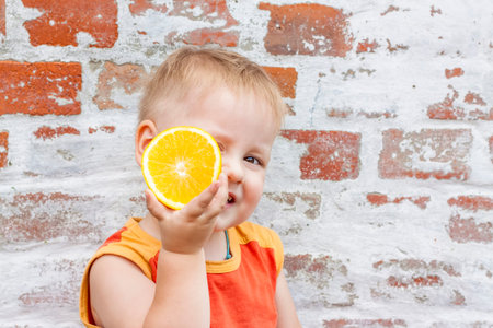 Portrait of child. Cute boy posing with an orange. The emotions of a child. Portrait of a boy...